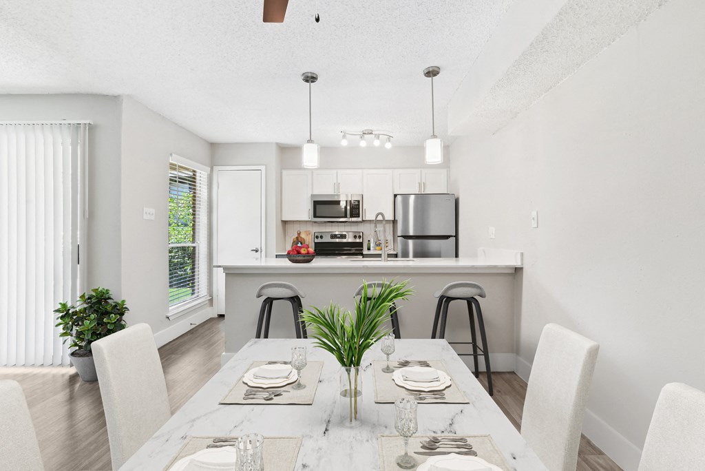 a dining area with a table and chairs and a kitchen in the background