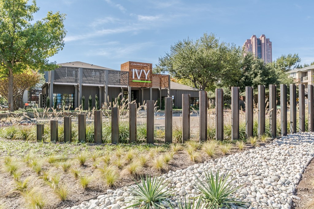 a view of the front of the building with a fence in the foreground and a building in