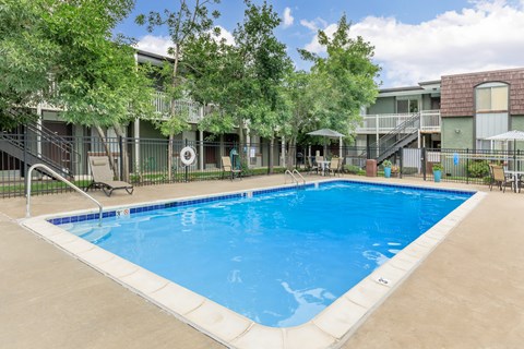 A large swimming pool surrounded by a fence and trees.