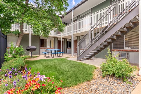 A patio with a table and chairs is surrounded by a garden.