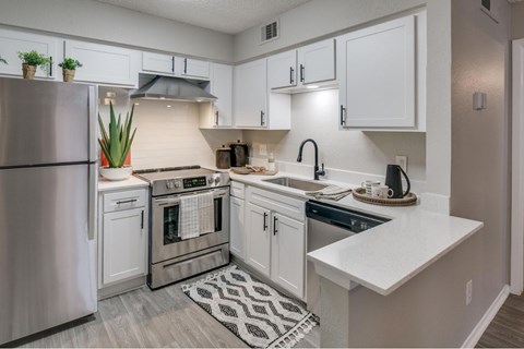 A modern kitchen with white cabinets and stainless steel appliances.