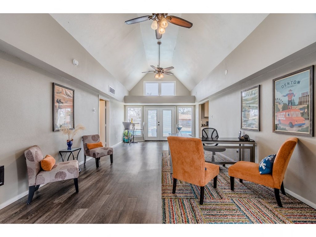 a spacious living room with a ceiling fan and chairs