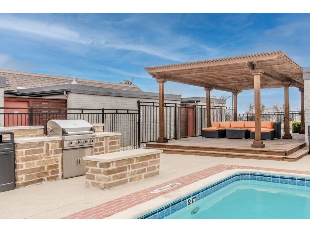 a backyard with a pool and a patio with a grill