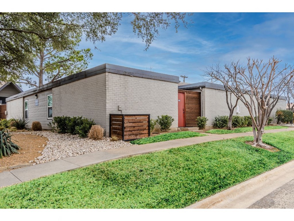 a white brick house with a driveway and a wood gate