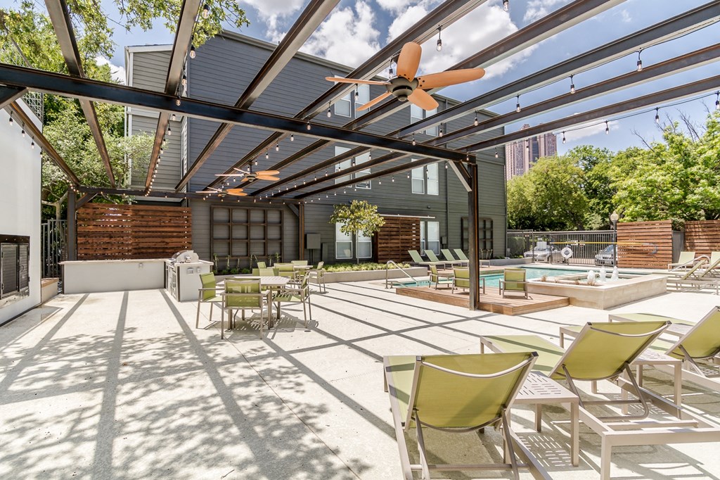 a patio with a pool and lounge chairs and a ceiling fan