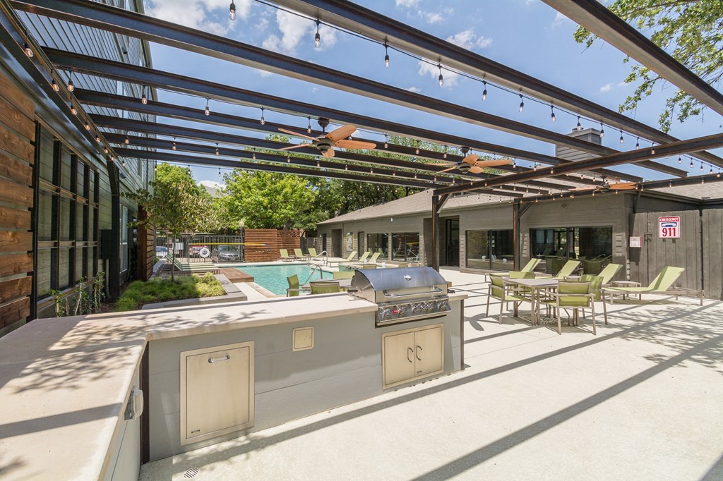 a patio with a grill and a pool in the background