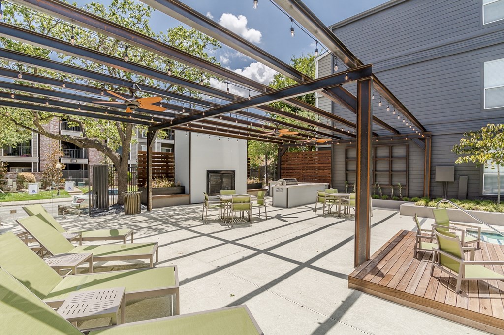 a patio with a fireplace and a pergola with chairs and tables