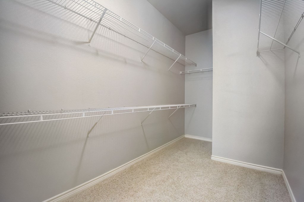 the walk in closet of a studio apartment with shelves and racks