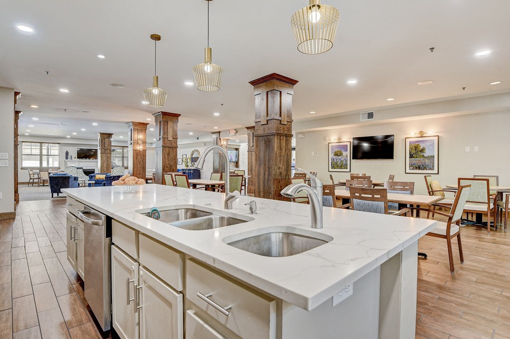 a large kitchen with an island and a dining room with tables and chairs