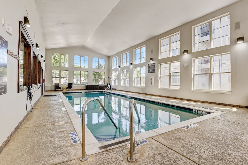 the indoor pool is spacious and has windows and a glass railing around it