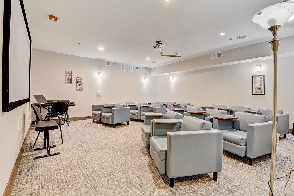 our theater room with couches and chairs and a piano