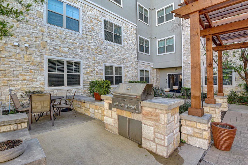 a backyard with a grill and a patio with a table and chairs