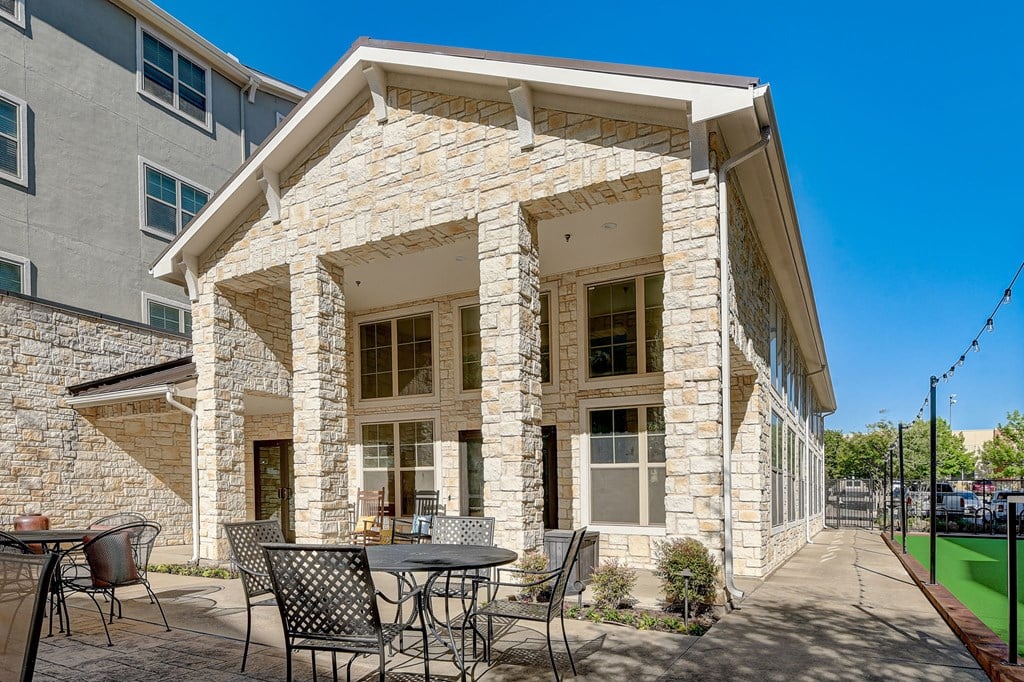 a patio with tables and chairs in front of a building