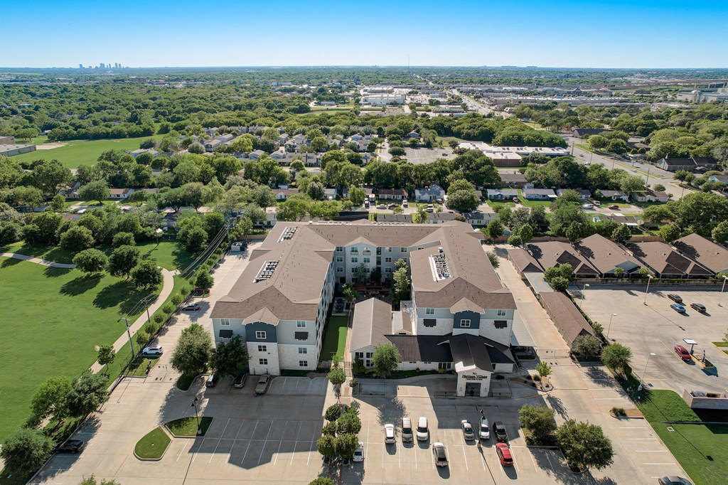 an aerial view of a large building in a neighborhood with cars on the street