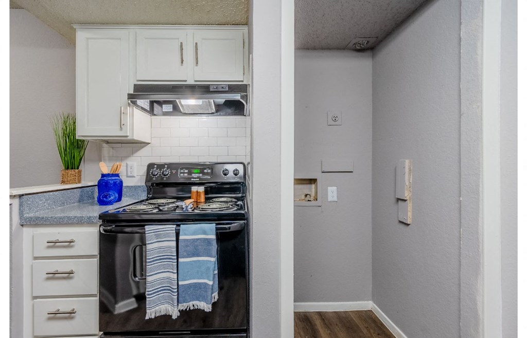 a kitchen with white cabinets and a black stove and oven