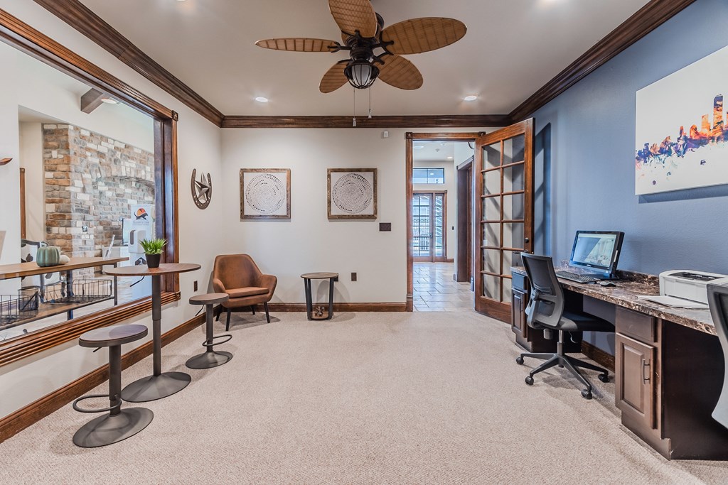 a home office with a computer desk and a ceiling fan