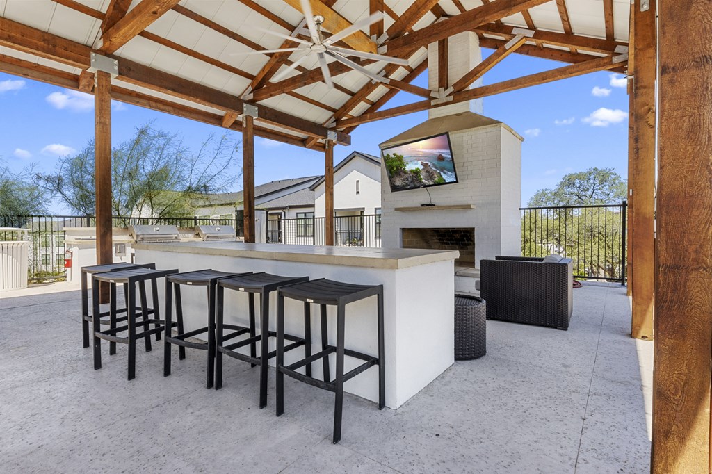a bar with bar stools under a roof with a fireplace