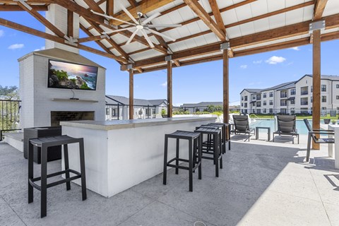 a patio with a bar and chairs and a building in the background
