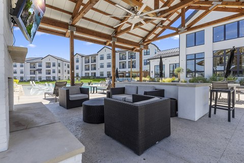 a patio with chairs and a bar and a building in the background