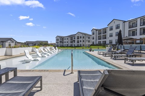 a swimming pool with lounge chairs and buildings in the background