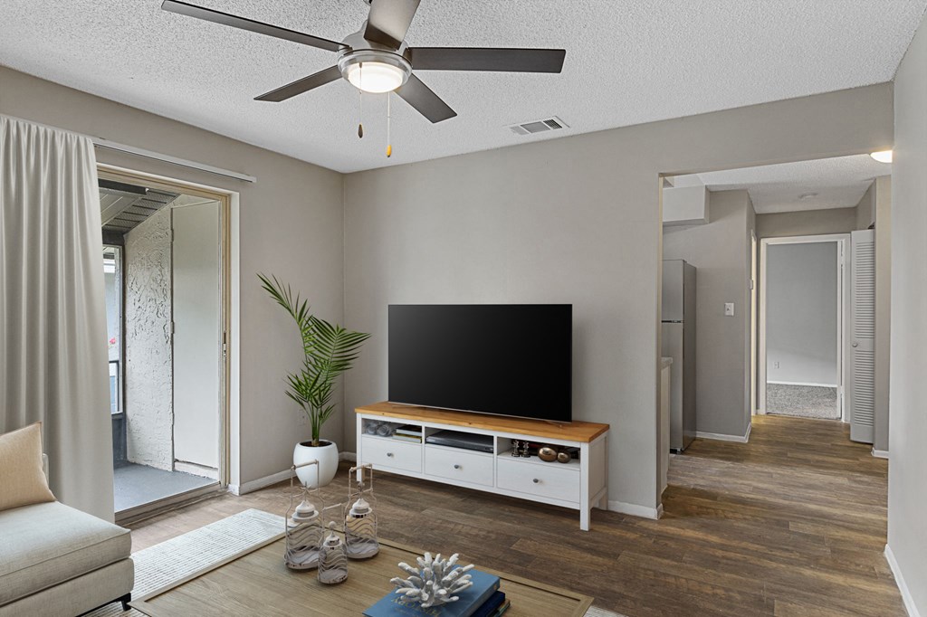 a living room with a ceiling fan and a flatscreen tv