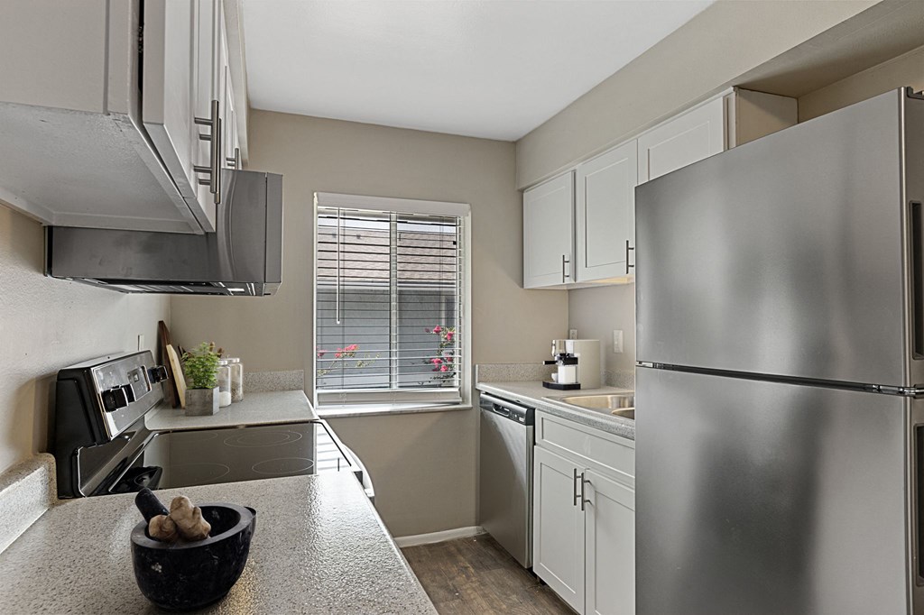 an empty kitchen with stainless steel appliances and a window