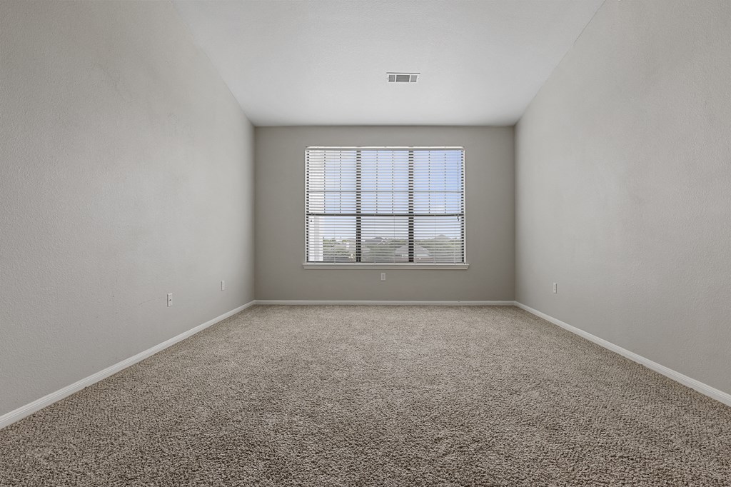 an empty room with a window and carpet