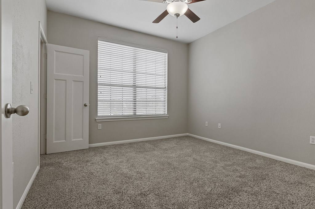 an empty bedroom with a ceiling fan and a window