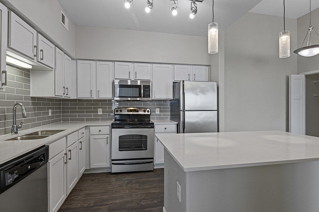 an empty kitchen with white cabinets and stainless steel appliances