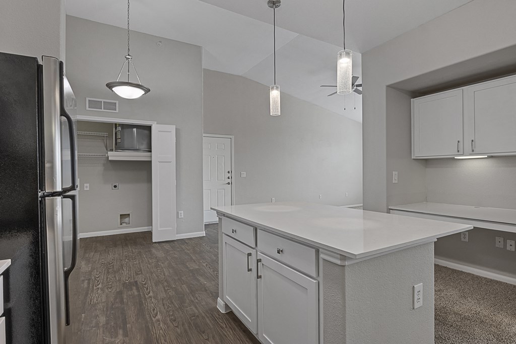 an empty kitchen with a white counter top and a refrigerator