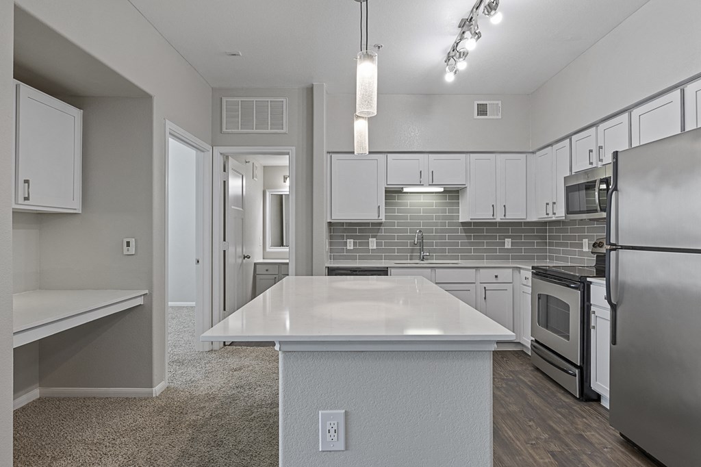 an empty kitchen with an island and stainless steel appliances