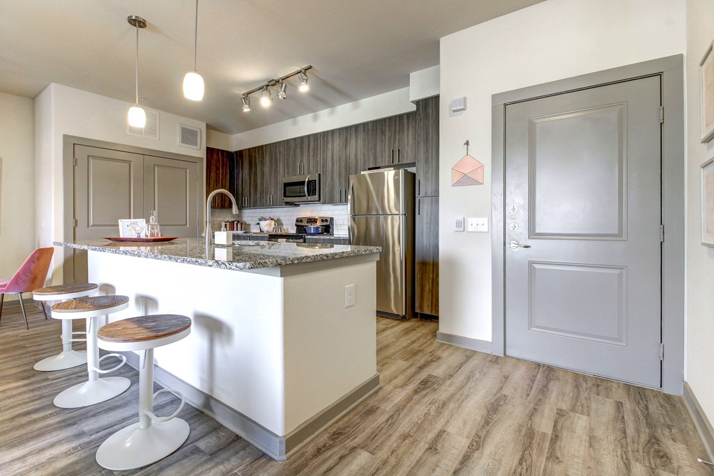 a kitchen with a bar and a stainless steel refrigerator