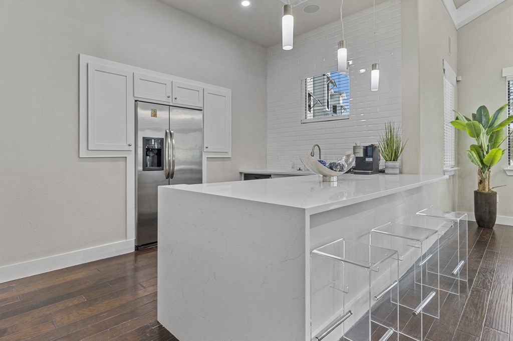 a white kitchen with a large island and white bar stools