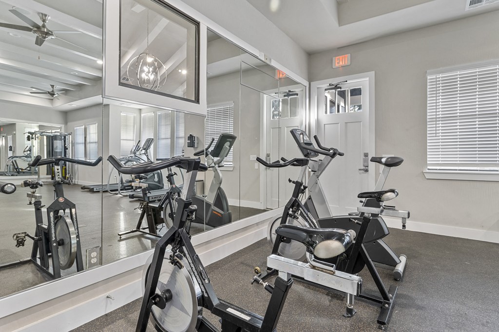 a gym with exercise bikes and a mirror in the wall