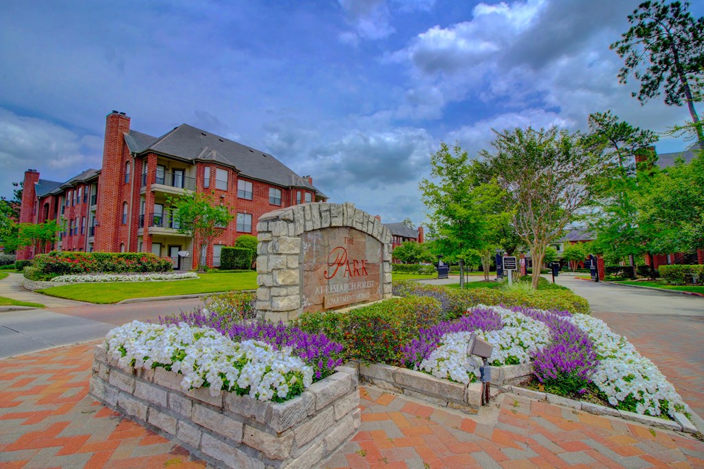 a large stone monument with flowers in front of it and a brick building in the background