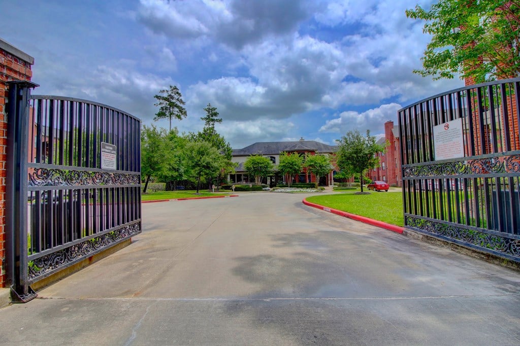 a pair of gates leading to a brick building with a grey roof