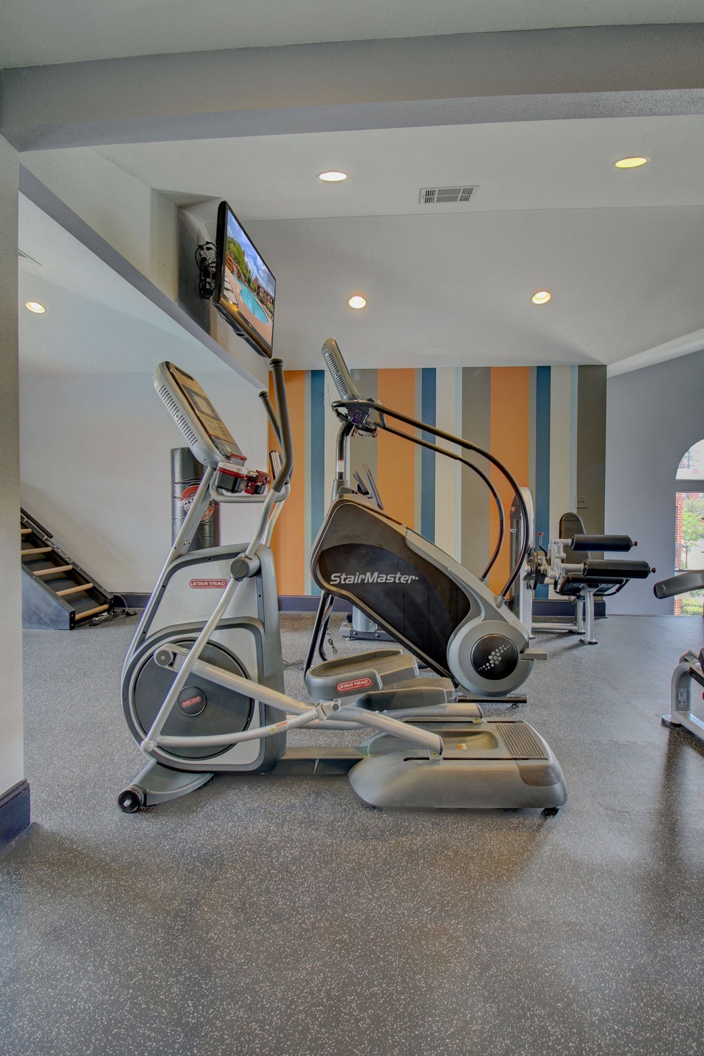 a gym with cardio equipment and a flat screen tv
