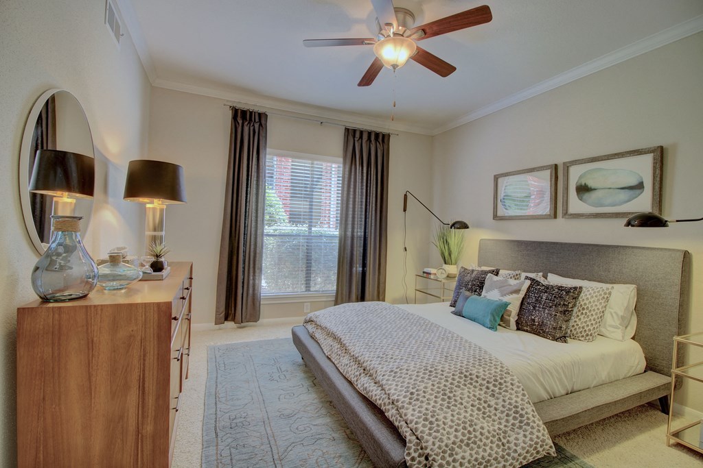 a bedroom with a ceiling fan and a large window