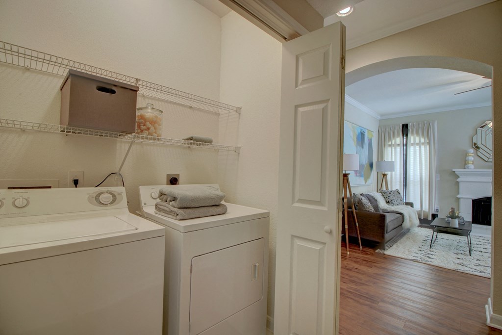 a laundry room with a washer and dryer and a living room in the background
