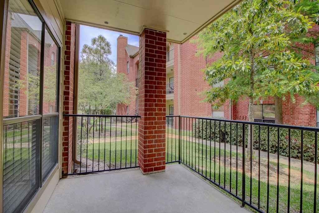 a balcony with a black railing and a brick building in the background