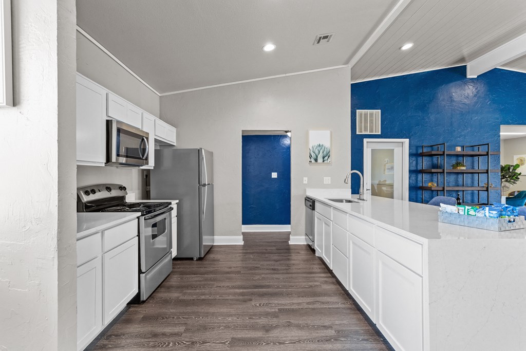 a kitchen with white cabinets and a blue wall