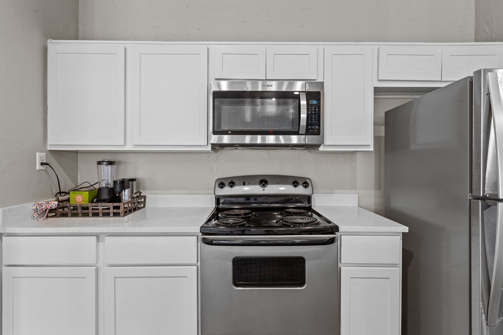 a kitchen with white cabinets and stainless steel appliances