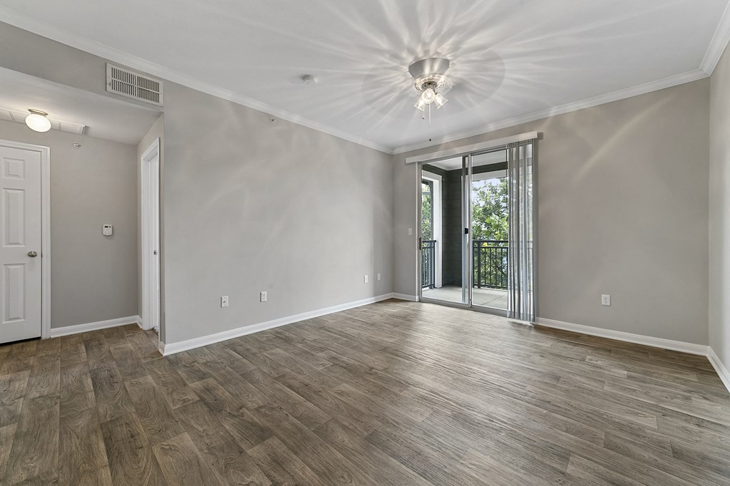 an empty living room with a sliding glass door to a balcony
