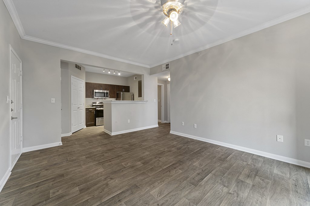 an empty living room with a kitchen in the background