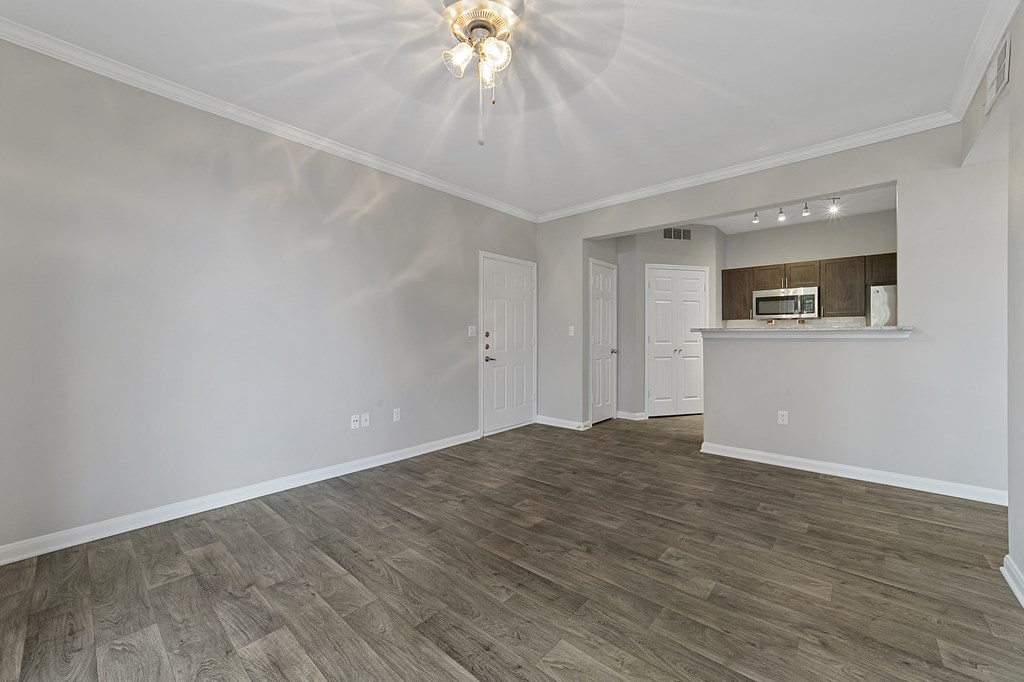 an empty living room with white walls and a kitchen