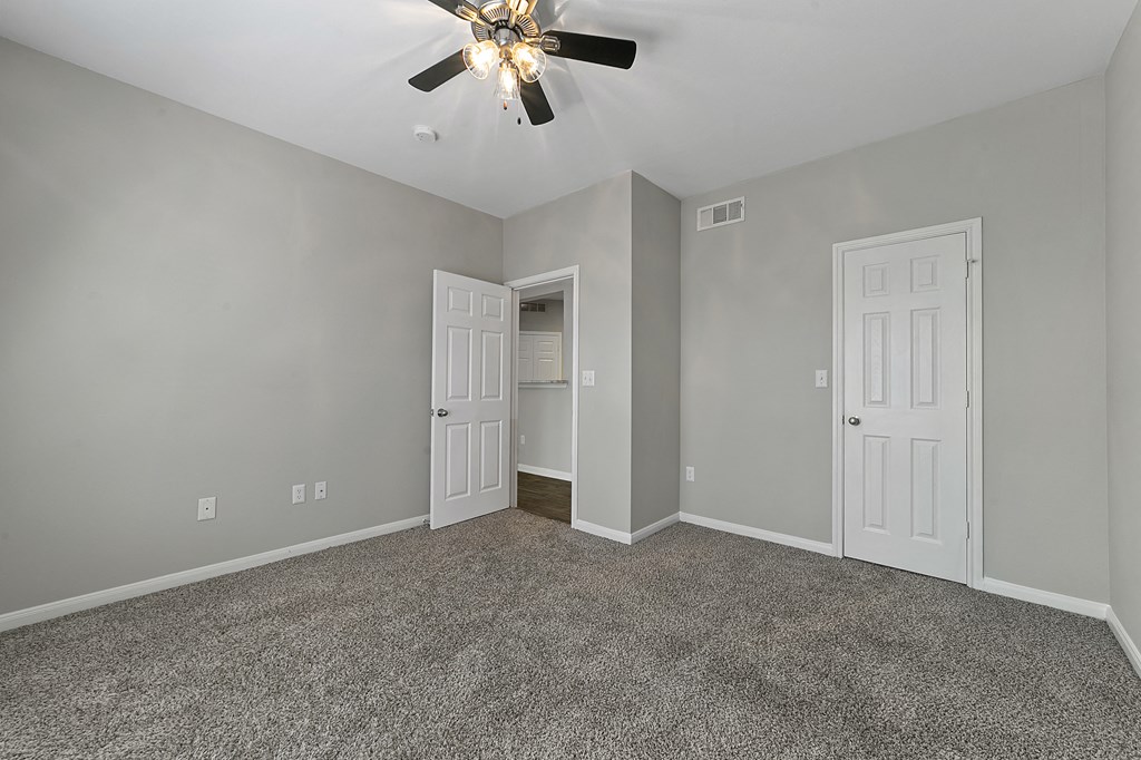 an empty room with two doors and a ceiling fan