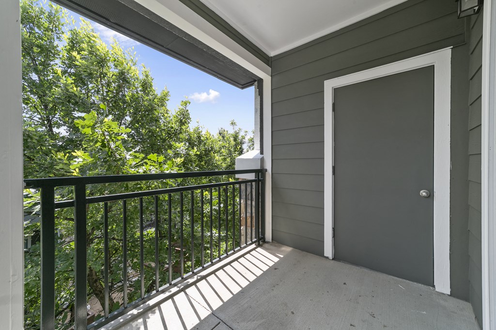 the view from the balcony of a home with a door to a balcony with trees
