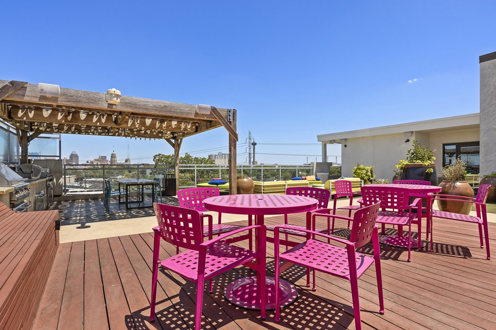 a patio with pink chairs and tables on a roof