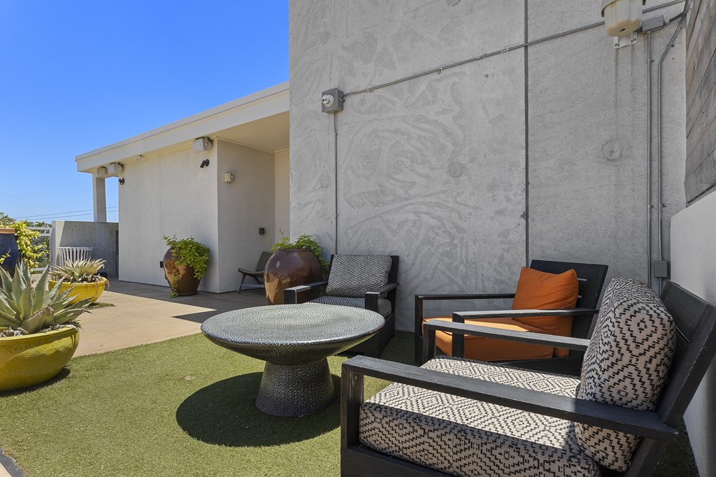 a patio with chairs and a table in front of a building