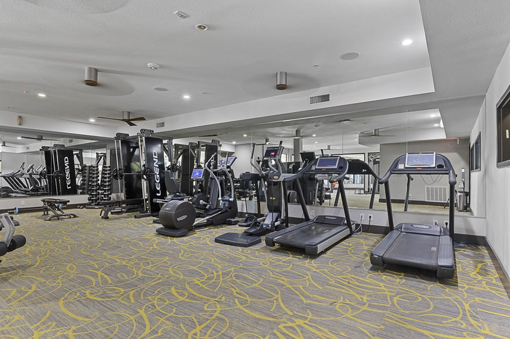 a gym with cardio machines and weights in a building with white ceilings
